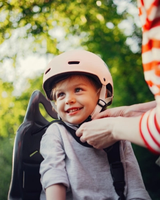 Mutter zieht ihrem Kind den Fahrradhelm an